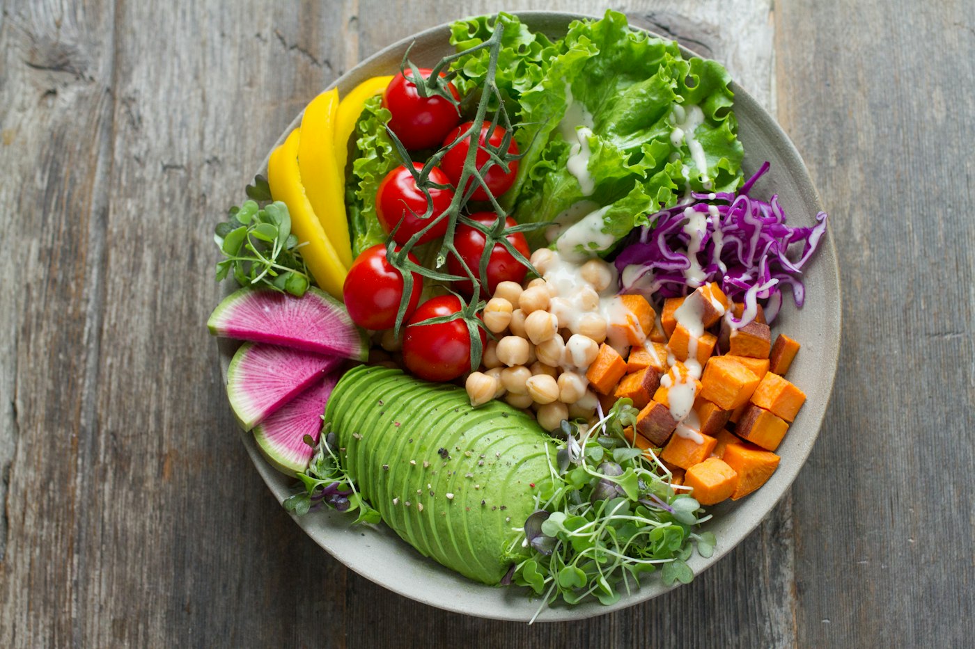 A colorful plant-forward bowl with greens, chickpeas, avocado, and roasted vegetables