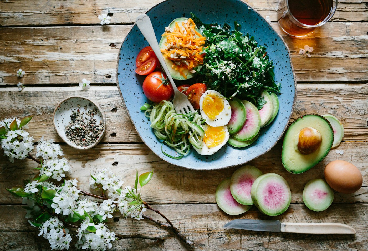 A fresh vegetable salad with avocado and eggs on a rustic wooden table